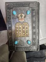 Front cover showing crown, gilt tablets, turquoise cabochons, embossed border