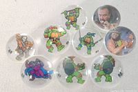 Group shot of nine marbles showing mix of TMNT and WWF graphics