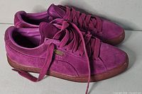 Side view of both sneakers showing suede uppers, laces, gum soles