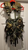 Front view of woodland camo tactical vest showing pouches and straps