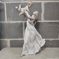 Full view of figurine showing mother lifting child