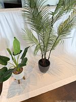 Both artificial plants side by side showing relative sizes and pots