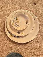 Stacked view of dinner plate, side plate and dessert bowl showing pattern and size relation