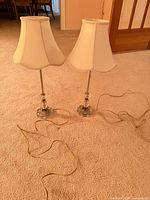 Front view of both glass and brass table lamps with shades and cords visible