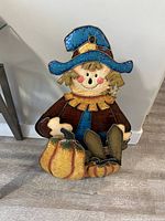 Full view of metal scarecrow figure standing against wall