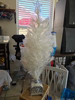 Full view of white fiber optic tabletop Christmas tree with star topper and silver base