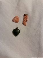 All three pendants laid out: pink coral heart, pink coral floral cluster, green heart