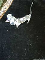 Side view of clear glass dachshund figurine on black fabric