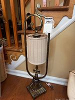 Full view of metal table lamp with shade standing on wood floor