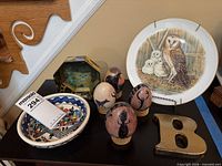 Group shot of eggs on stands, owl plate, bowl, brass letter, trinket box