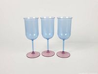 Front view of three matching blue bowl, pink stem Guzzini goblets