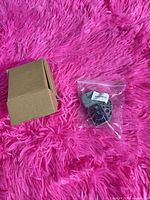Cardboard box and sealed plastic bag containing grey camshaft/crankshaft position sensor