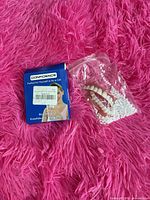 Front of Confidence kit box next to bag containing veneer teeth and beads