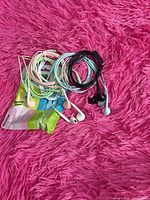Coiled pastel and black earbuds plus partial retail packaging on pink surface