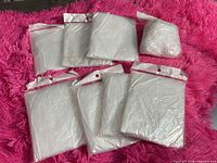 Eight individually packaged transparent raincoats laid out
