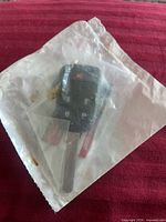 Front view of black car key fob with metal blade inside plastic bag