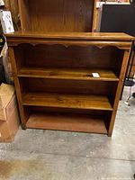 Front view of wood bookshelf with two shelves and scalloped trim