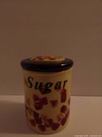 Front view of yellow ceramic sugar canister labeled Sugar