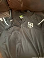 Full view of black Reebok LA Kings polo shirt front