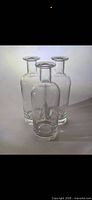 Three clear glass bottles standing, showing shape and clarity