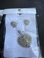 Front view of pendant and earrings on card inside sealed bag
