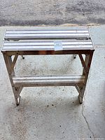 Top view of aluminum 2-step stool showing ribbed steps and lot sticker