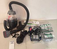 Full lot view: vacuum, hose, nozzle, charger, battery pack, Hoover bags, EZ Spares filters