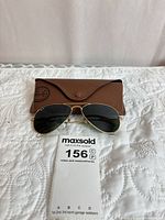Sunglasses on top of brown Ray-Ban case with lot tag visible