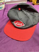 Front view of black cap with red brim and Dairy Queen logo