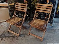 Two assembled wooden slatted folding chairs standing