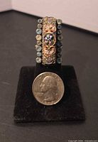 Front view of ring on stand with quarter for scale