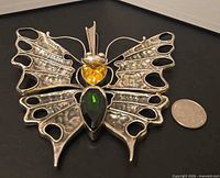 Full view of large sterling silver butterfly pendant beside coin for scale