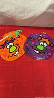 Two plastic Halloween treat bags, orange and purple, cartoon monster faces