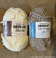 Front view showing both labeled skeins: Bernat Blanket Vintage White and Bernat Baby Blanket Baby Sand