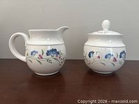Front view of porcelain creamer and lidded sugar bowl showing pattern and shape