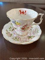 Teacup on saucer showing floral design and Canadian flag inside cup