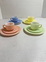 Four pastel place settings with cups on saucers and plates