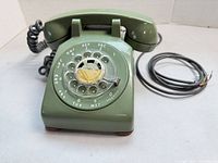 Front view of olive green Northern Electric rotary dial telephone with handset and cords