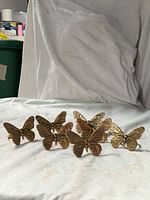 Front view of all seven brass butterfly napkin rings
