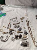 Overview of all jewellery, buckles, rings, spoon and chains laid out on cloth
