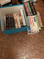 Overview showing blue box filled with VHS tapes plus additional stacks of westerns, sports bloopers and Spartacus tape