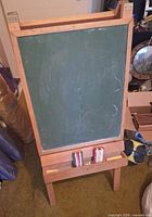 Front view of wooden easel with green chalkboard, chalk tray and two erasers visible