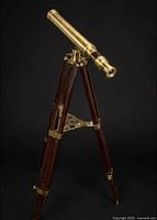 Full view of brass telescope on dark wood tripod