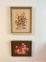 Both framed embroidered panels hung on wall