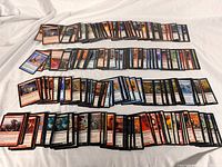 Four rows of assorted Magic: The Gathering cards laid out face-up on white backdrop