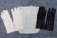 Black and white leather glove pairs with note displayed flat
