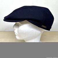 Side view of dark navy wool ivy cap on mannequin displaying overall shape and earflap seam