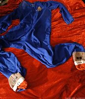 Full view of blue onesie pajama laid flat showing chest applique and sock-puppet footies