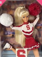 Close-up of doll’s upper body, uniform detailing, face and pom-poms