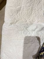 Close-up of white quilted section showing fabric texture and stitched floral patterns